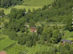 Bolighus med  grønnsakhage og mange trær rundt.