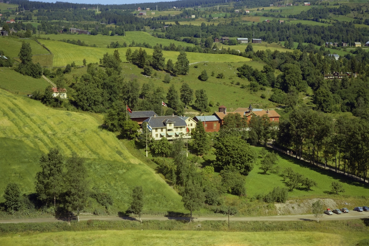 Aulestad. Museum. Hvit hovedbygning, hvit sidebygning. Lang driftsbygning. Flere mindre hus. Parkanlegg, allé, flaggstenger med nordiske flagg..