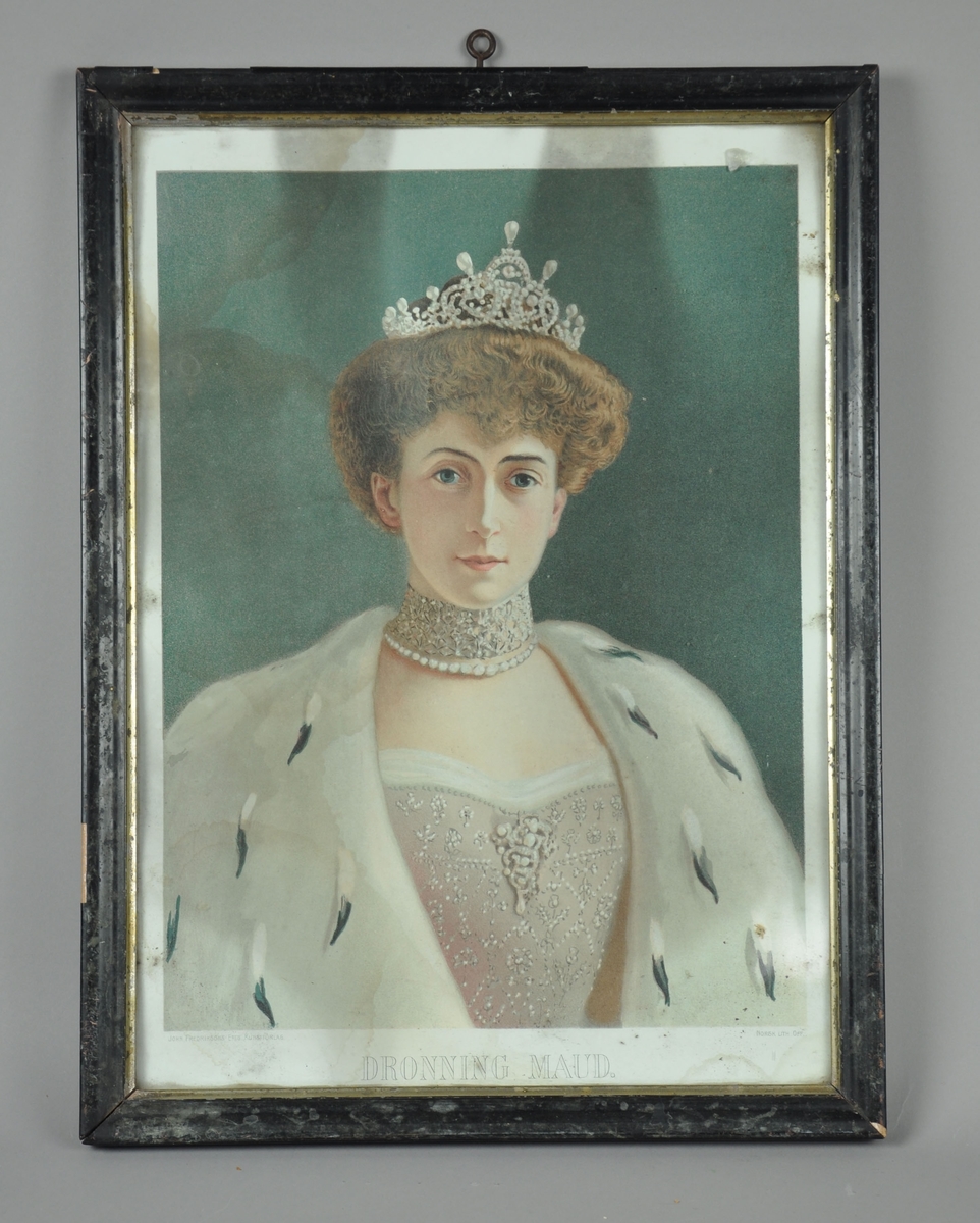 Innrammet portrett av Dronning Maud. Svart innramming med kanter av sølv på innsidene. Både papir og ramme er noe slitt.