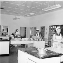 Fra kjøkkenavdelinga. Matlaging. Unge kvinner med forklær st