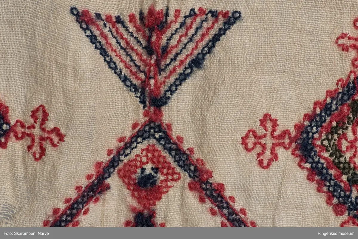 Kvadrater stilt på høykant, små kors og 8 armete staker? Motivene er stilt i rader over hele duken. Gjenombrutt bord med kvadrater i en kortende