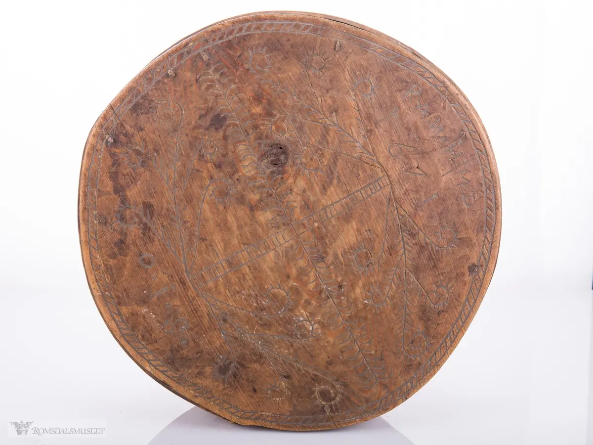 Eit kvistmønster/bregner på lokk. Skravert kryss- mønster langs trosken. Rosett av spetter i bunnen.