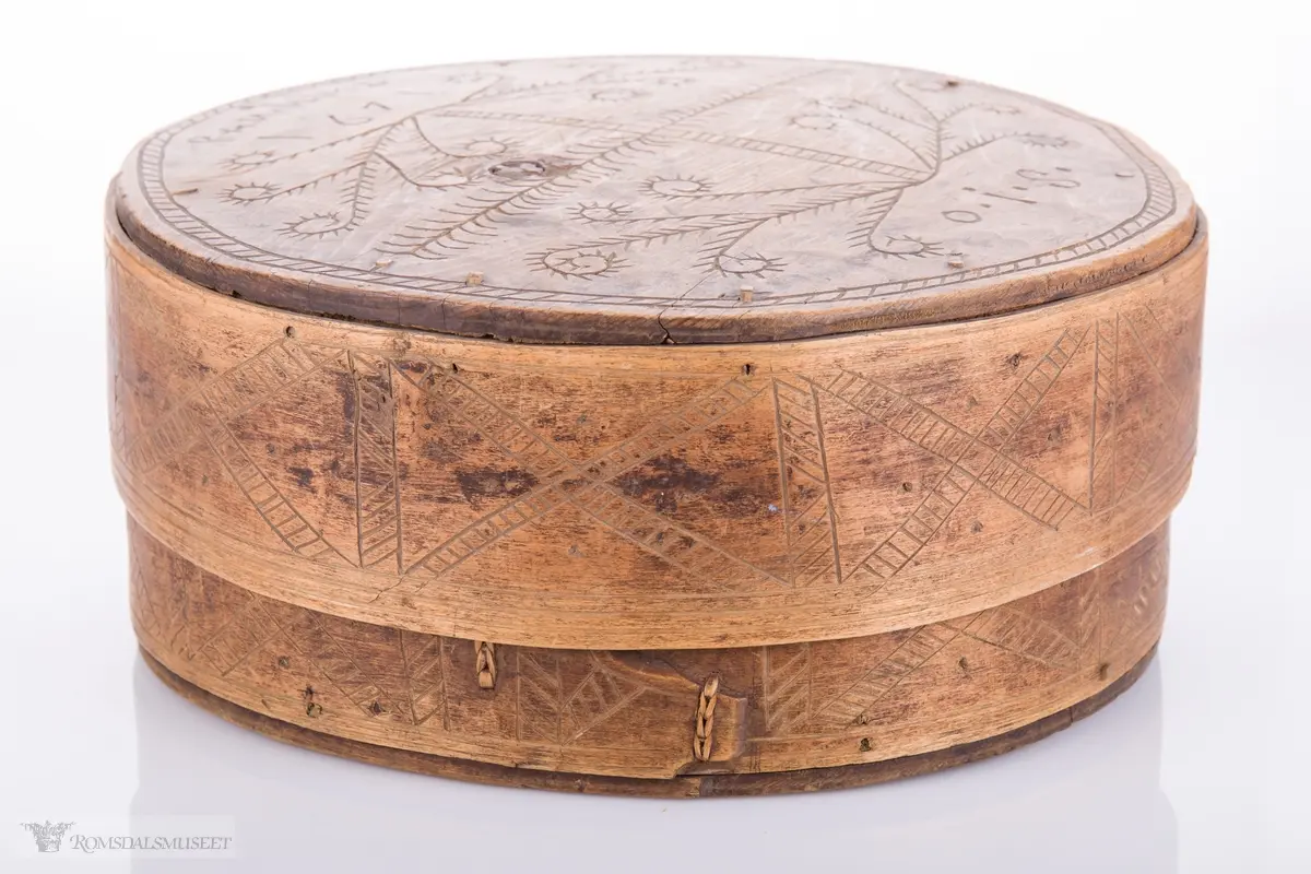 Eit kvistmønster/bregner på lokk. Skravert kryss- mønster langs trosken. Rosett av spetter i bunnen.