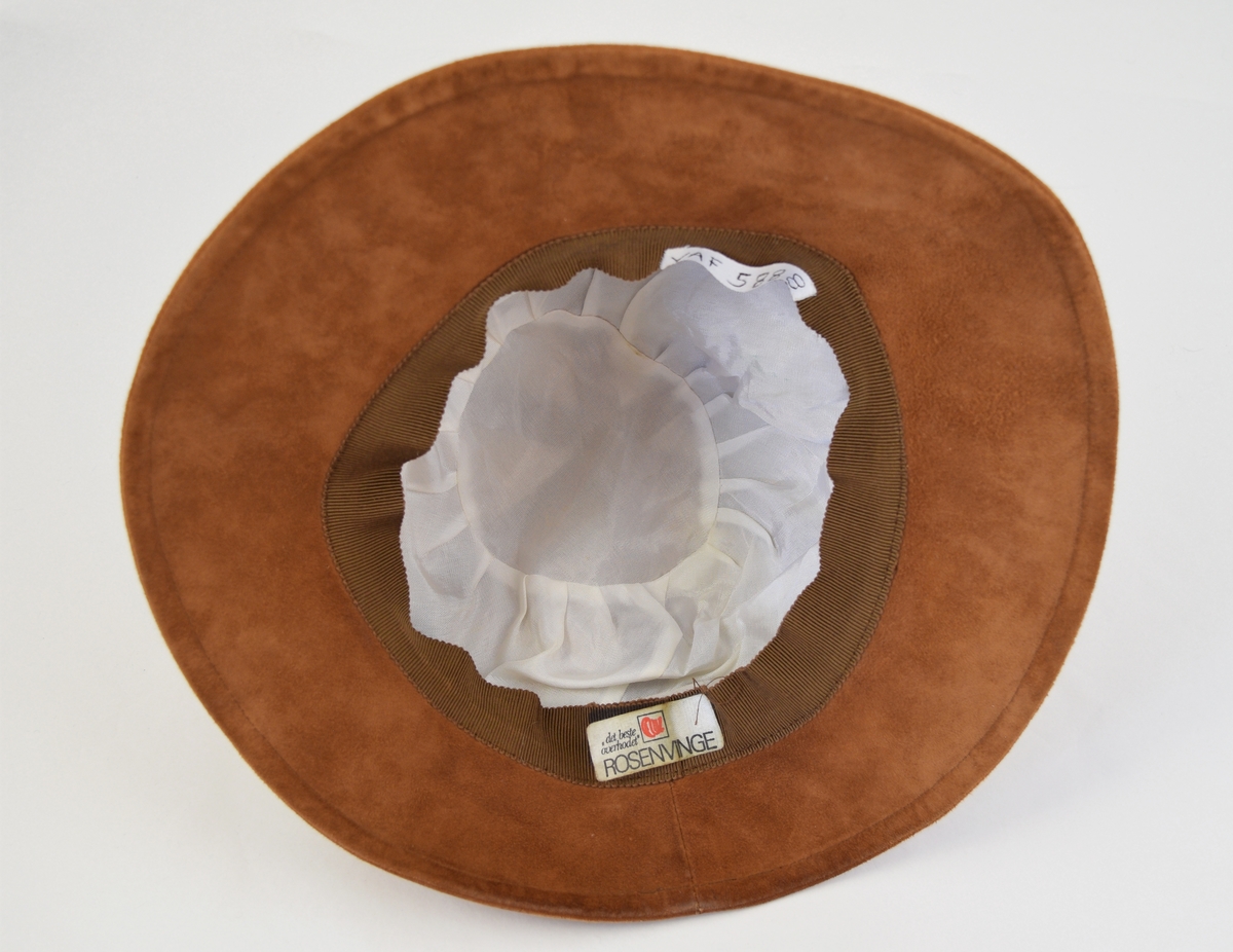 Hatt av semsket skinn.  Hatten er rund med brem, bremmen er noe smalere på hattens bakside. Hoveddelen består av seks trekantede stykker og bremmen består av et stykke. Foret med tynt hvitt stoff på innsiden.