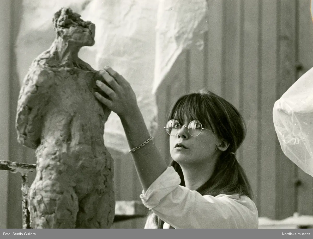 En elev vid Konstfackskolan modellerar en skulptur i lera.