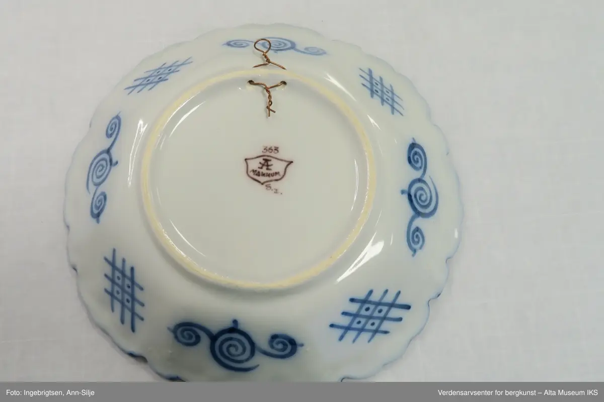 Fat, eller skål, med rund base, og svakt 8-kantet korpus og tunget kant. Motivet i fatet er ornamentalt blomster-, fugle- og sommerfuglmotiv. På baksiden er det motiver av spiraler og ruter.