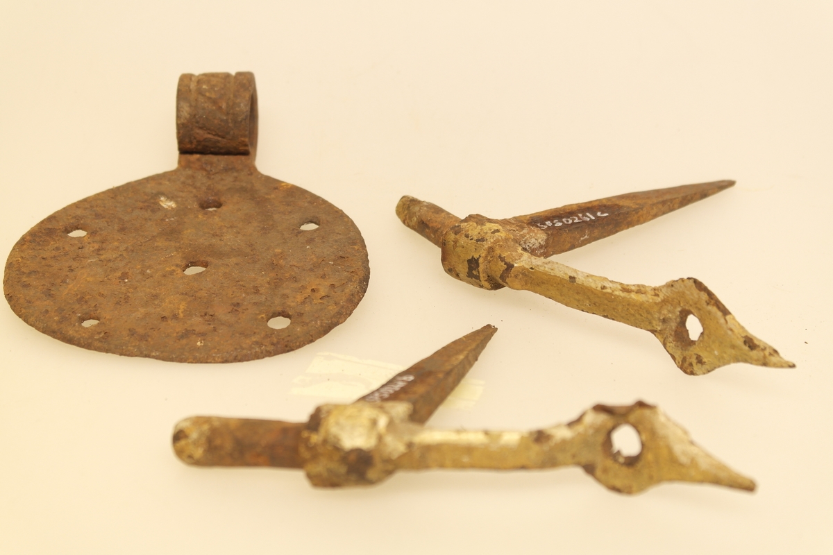 2 hengsler og 1 gjenge i smidd jern. Hjerteformet beslag på hengslene. Rundt beslag med 6 naglehull.
Ornament på gjengjernet.