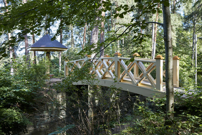 En bro går over til en paviljong i skogen. 