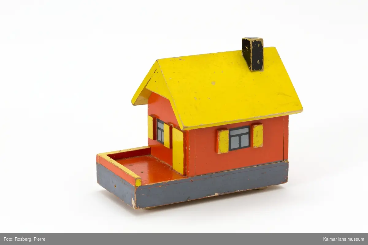 KLM 45110:2. Hus på hjul, leksak, av trä. Taket fungerar som ett lock och går att ta av. Huset målat i rött, gult och svart. På undersidan text: 516 samt 2 kr.