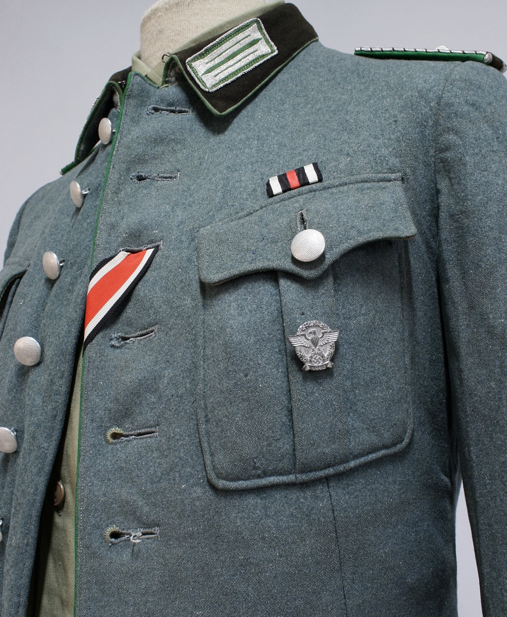 Full uniform med støvler. På brystet har den en pins (Politiets dag 1942), en bånd (Minne-/deltakermedalje 1914-1918) og EK. 2. klasse bånd. Den har også fløyte i brystlommen. 

Skulderdistinksjoner til en oberwachtmeister

I lommen var det stoff lapper og sytråd med nål. 

På beltet har den pistolhylster med Walther PP magasin.