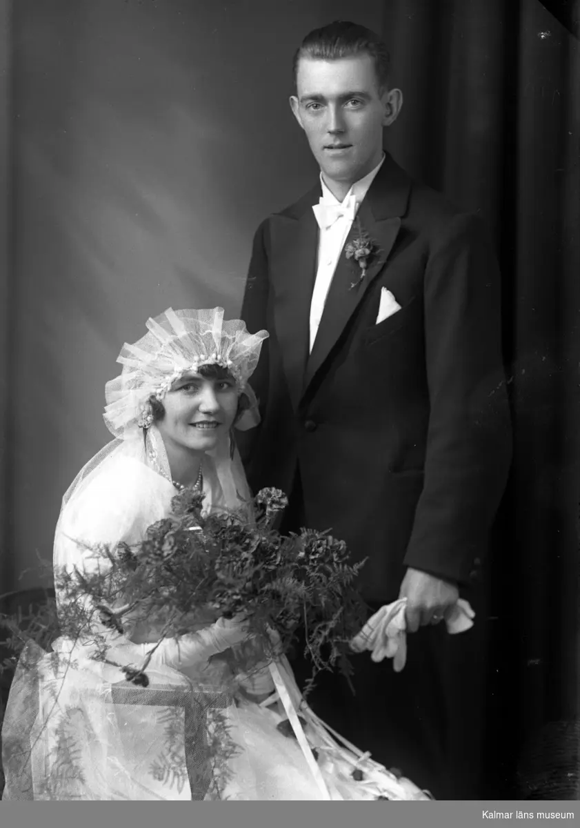 Bröllopsbild. Kvinnan håller i en blombukett och har en slöja. Beställare till bilden: Herr Nils Melin ifrån Kalmar.