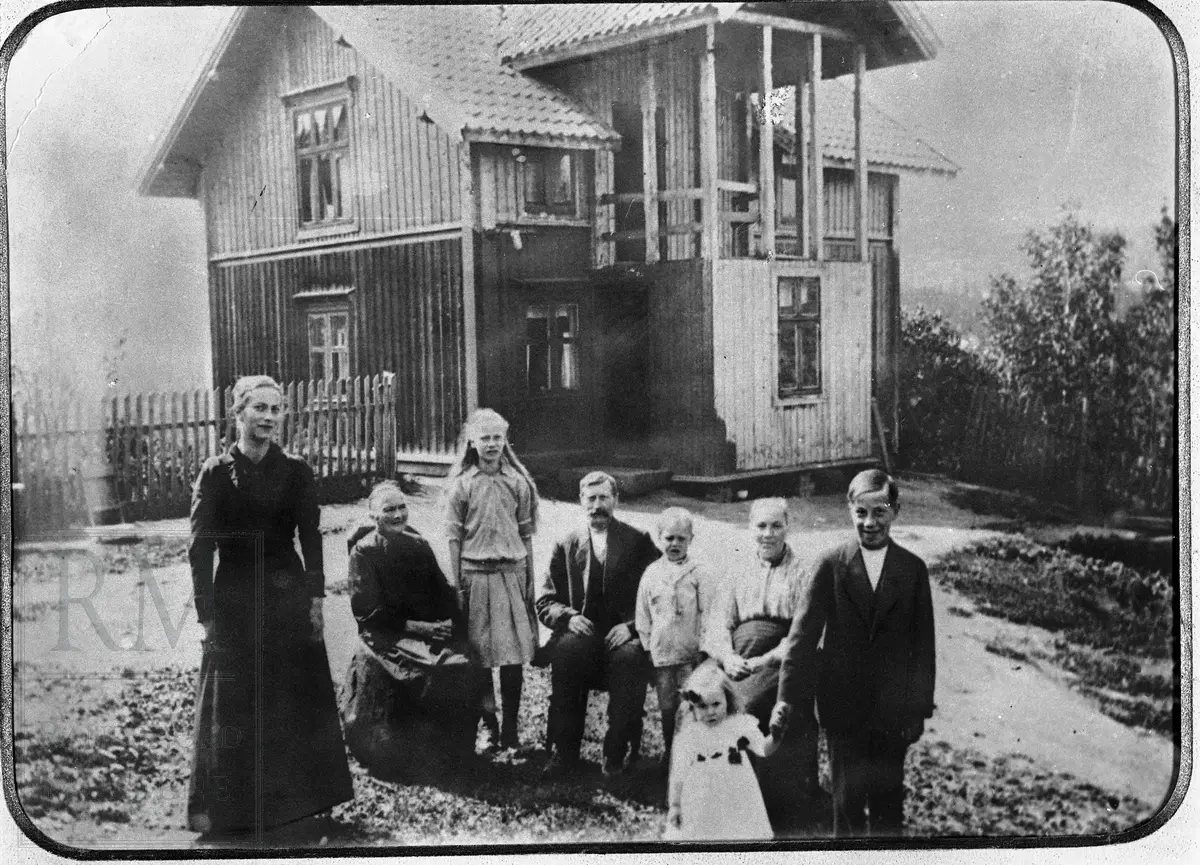 En familie samlet foran et hus.