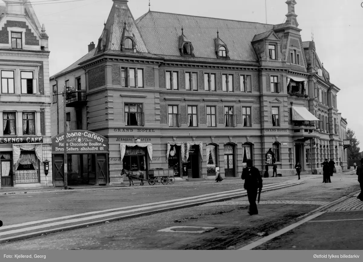 Grand Hotel i Hamar med Jernbanekafeen. Til venstre Søstrenes Ilsengs cafe. I første etasje på hotellet ligger forretningen til urmaker A. M. Sveen. 
Lengst til høyre kan man skimte reklameskilt for fotograf Inger Barth (1858-1952).