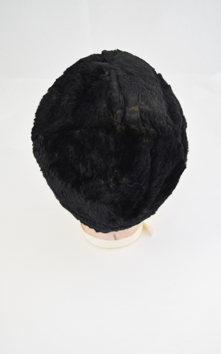 Hatt eller lue av pels. Rund form. Foret med ull dekket av et tynnere stoff. Foret er sydd med sømmer som former en rose eller stjerne på  innsiden av hatten.