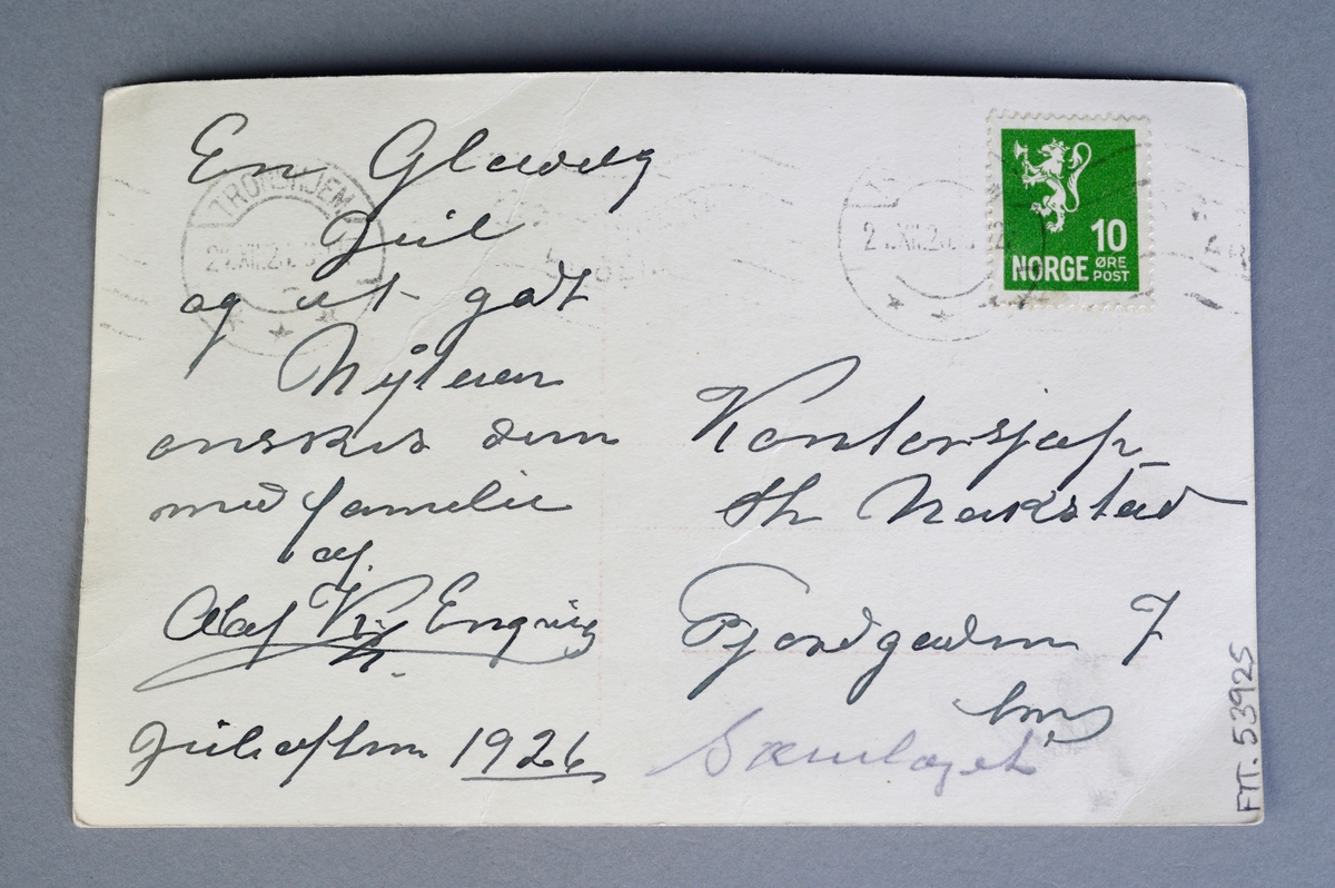 Firkantet postkort som er sendt som julehilsen sendt i 1926. Motivet på postkortet er et sort-hvitt fotografi fra Trondheim, nærmere bestemt Skansen/Ila. På baksiden er det skrevet en julehilsen (se "Andre opplysninger"). Det er også et grønt frimerke og poststempel på baksiden.