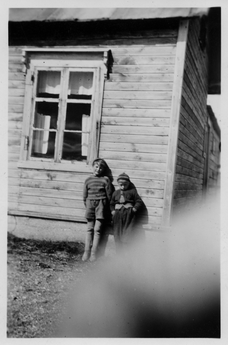 To gutter står oppstilt mot husveggen. Huset er Varangerhuset på Slettmoen i Golnes, i sin tid bygget av Johan Kandola.