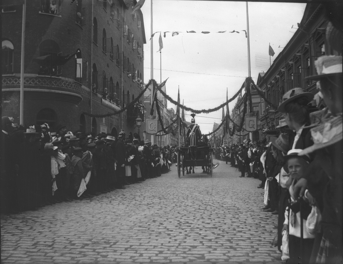 Drottninggatan smyckad till utställningen 1901. Troligtvis kungens eller kronprinsens ankomst. Kronprisen kom med extratåg den 7 juli 1901 och kungen den 8 juli kl 09.30. Drottninggatan med kv Gunstlingen till vänster och kv Armfelt till höger.