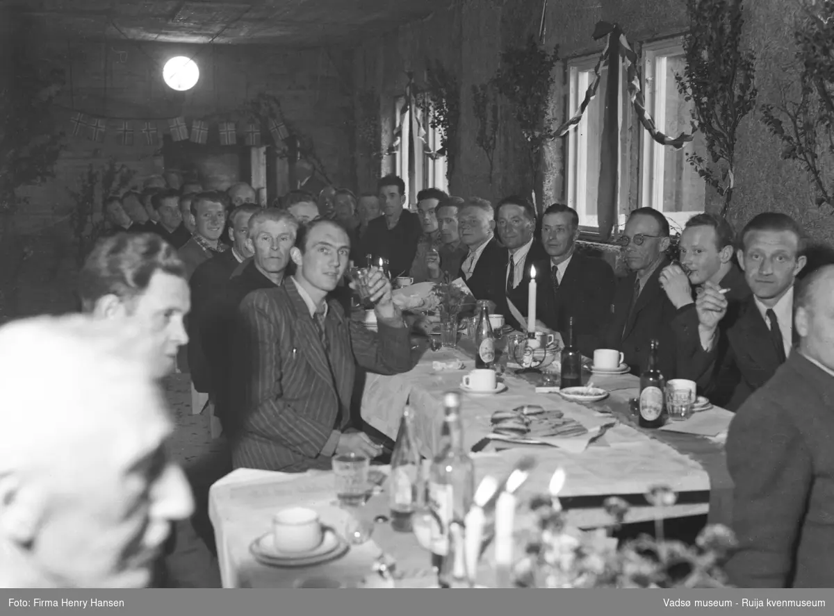 Bildet viser kranselaget på Finnmark Kringkaster i august 1948. Vi ser et langbord dekket med flasker og glass. Rommet er pyntet med løv og norske flagg.