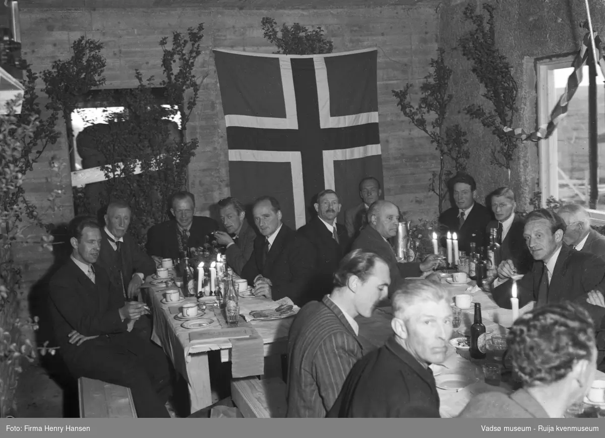 Bildet viser kranselaget på Finnmark Kringkaster i august 1948. Vi ser et langbord dekket med flasker og glass. Rommet er pyntet med løv og norske flagg.