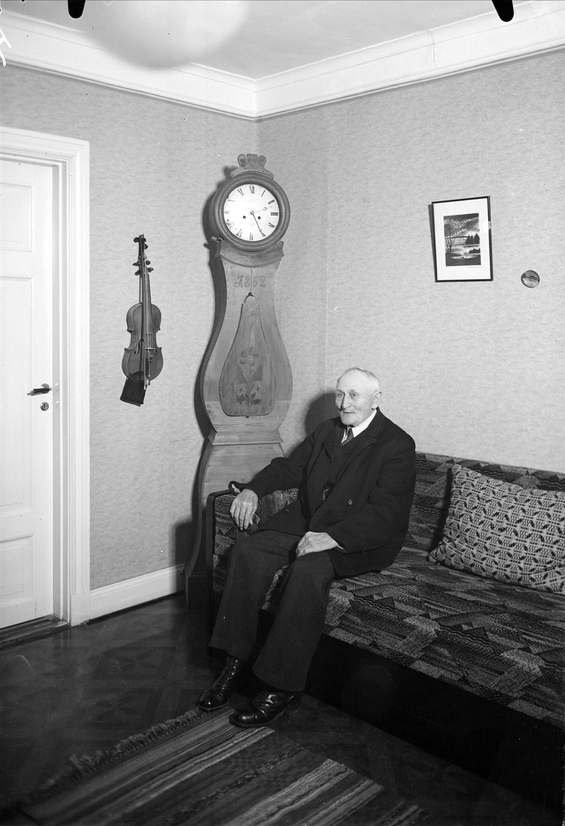 Man sitter i soffa hos Petterssons, Storvreta, Uppland 1938