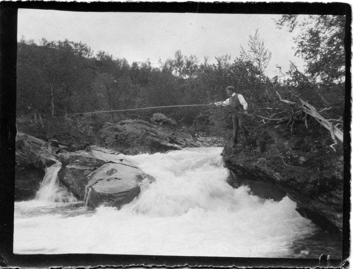 John Bauers Lapplandsresa sommaren 1904. Vid en fors vid sjön Kårsavaggejokk står John och väntar på att fisken ska nappa.