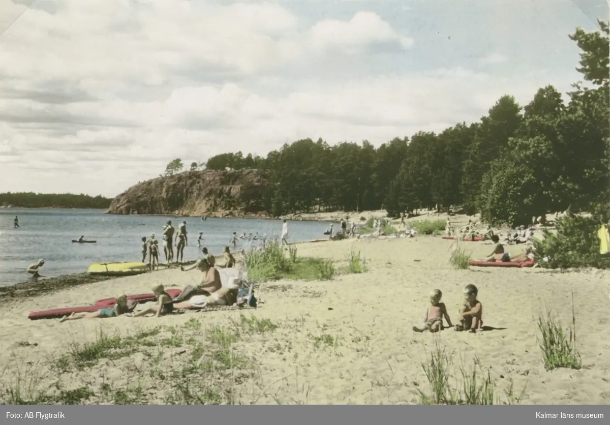 Kolorerat vykort med sandstrand vid Hallmare. Traktens skärgårdskaraktär framgår särskilt av klippan i bakgrunden på bilden, som kan vara tagen i slutet av 1960-talet.