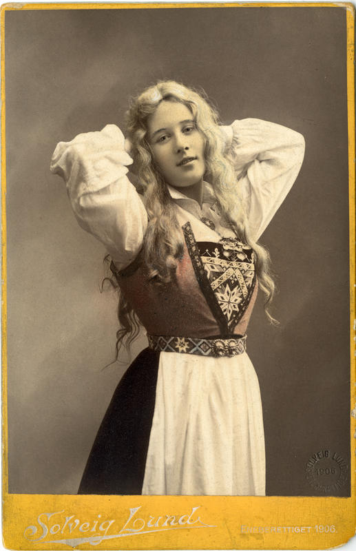 Kolorert studiofotografi av kvinne med harangerdrakt og utslått  hår. 1906. (Foto/Photo)