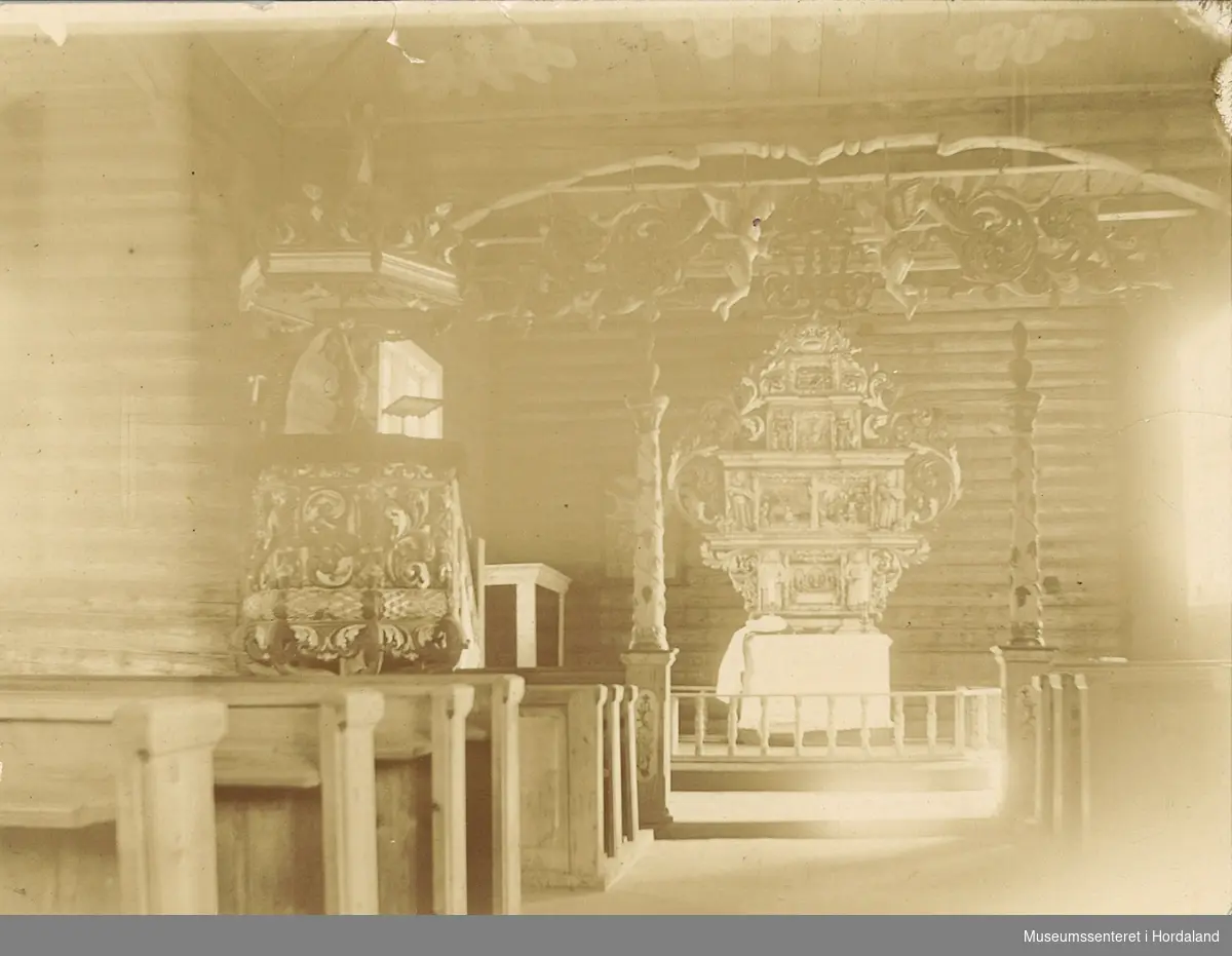 amatørfotografi av interiør frå skipet i ei gamal krosskyrkje med benkerader, preikestol og alter/kor