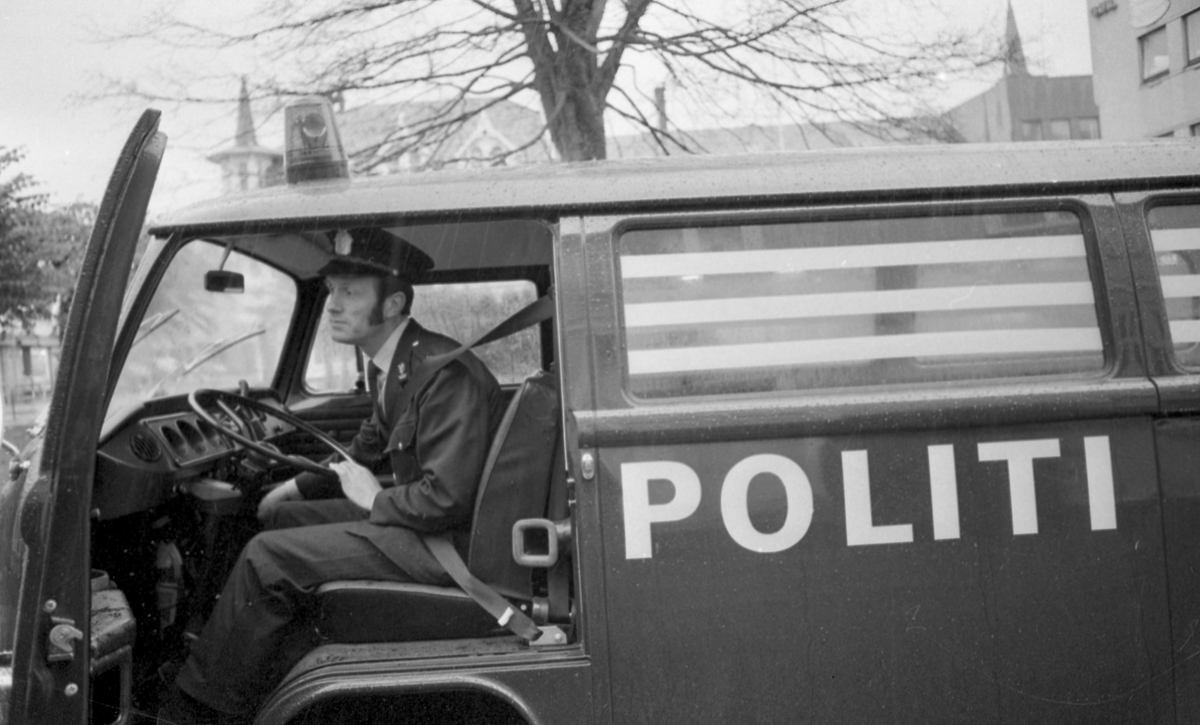 Sikkerhetsbelter hos Politiet. En politimann i uniform viser riktig bruk av sikkerhetsbelte i bil.
