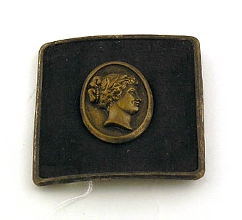 Bältesspänne, endast ena halvan, klätt med svart tyg, å detta en medaljong med kvinnohuvud.