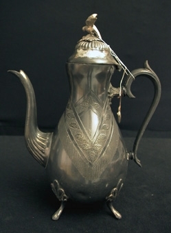 Päronformad kaffekanna av Britannia med ornament i form av ett nedhängande band med blad och fransar på vardera sidan. Knappen på locket är i form av en fågel och sitter löst.