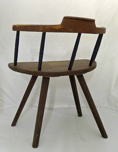 Brunmålad stol med 4 st 8-kantiga utställda, intappade ben. Halvcirkelformad sits, halvrund rygg bestående av 5 st svarvade ngt bakåtlutande pinnar, svängt krön med uppsvängt mittparti.