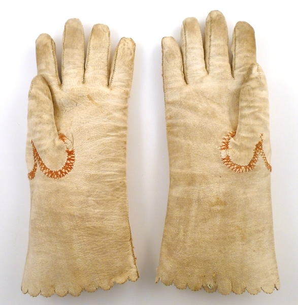 Handskar av vitt skinn med broderier i brunt, gult och grönt. Runt fingrarna och sidsömmen kråkspark i brunt silke.