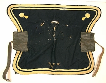 Enl liggare: "Sadeltäcke, av mörkblått kläde med gul bård."

Foder i linne. Hål för remmar är förstärkta med läder.