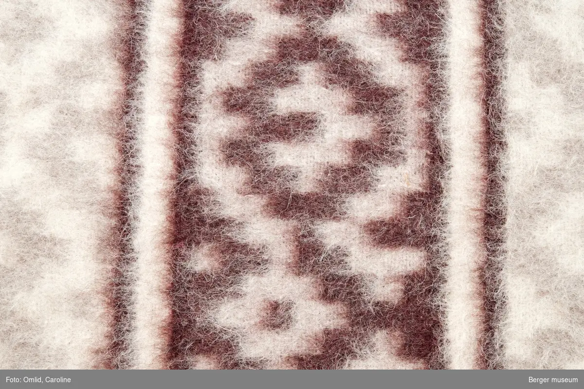 Teppeprøve med ruter utviklet fra korsmønster, med bord i liknende mønster innrammet av en stripe. Teppet i beige toner, borden i mørk burgunder.