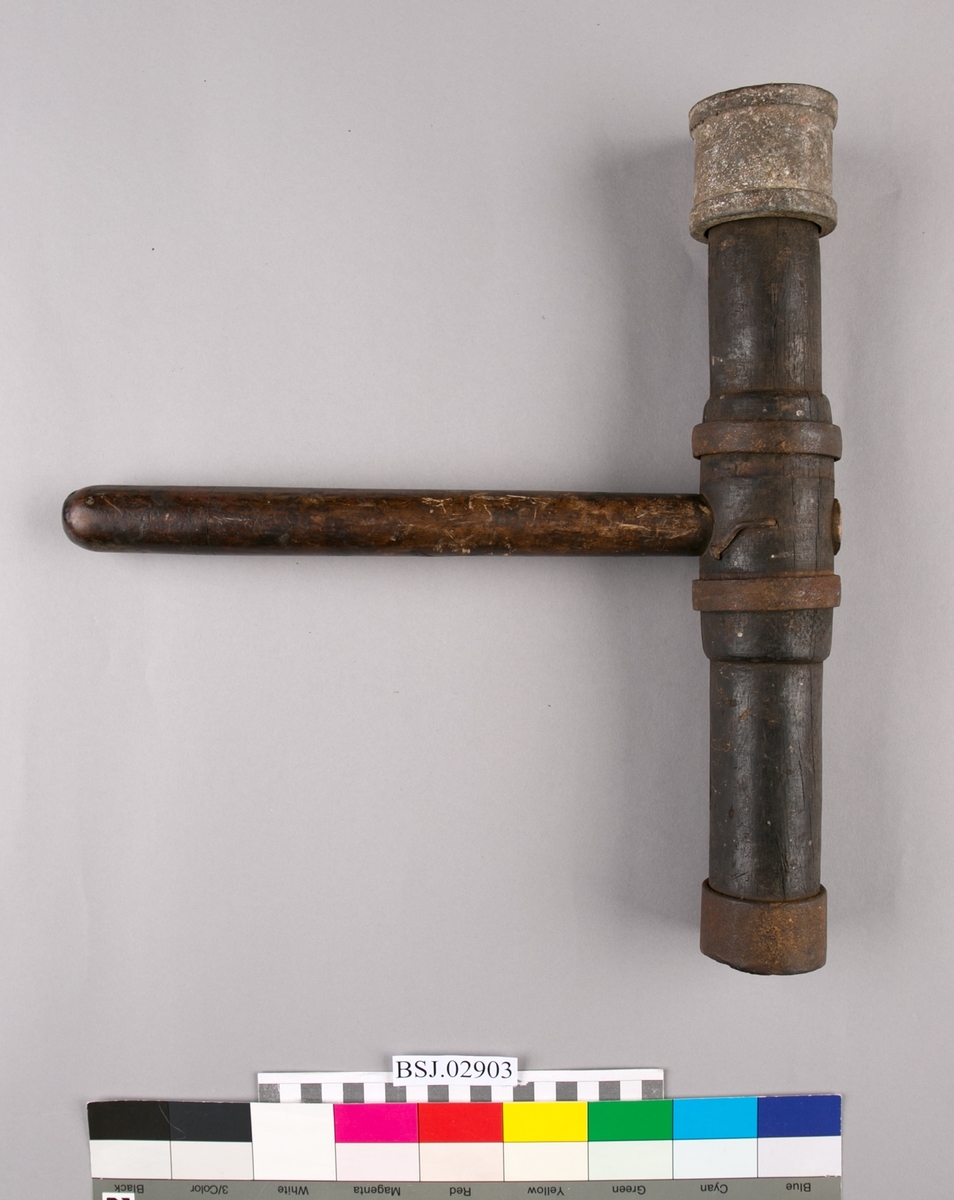 T-formet drivhammer av tre med jernbeslag i hver ende.