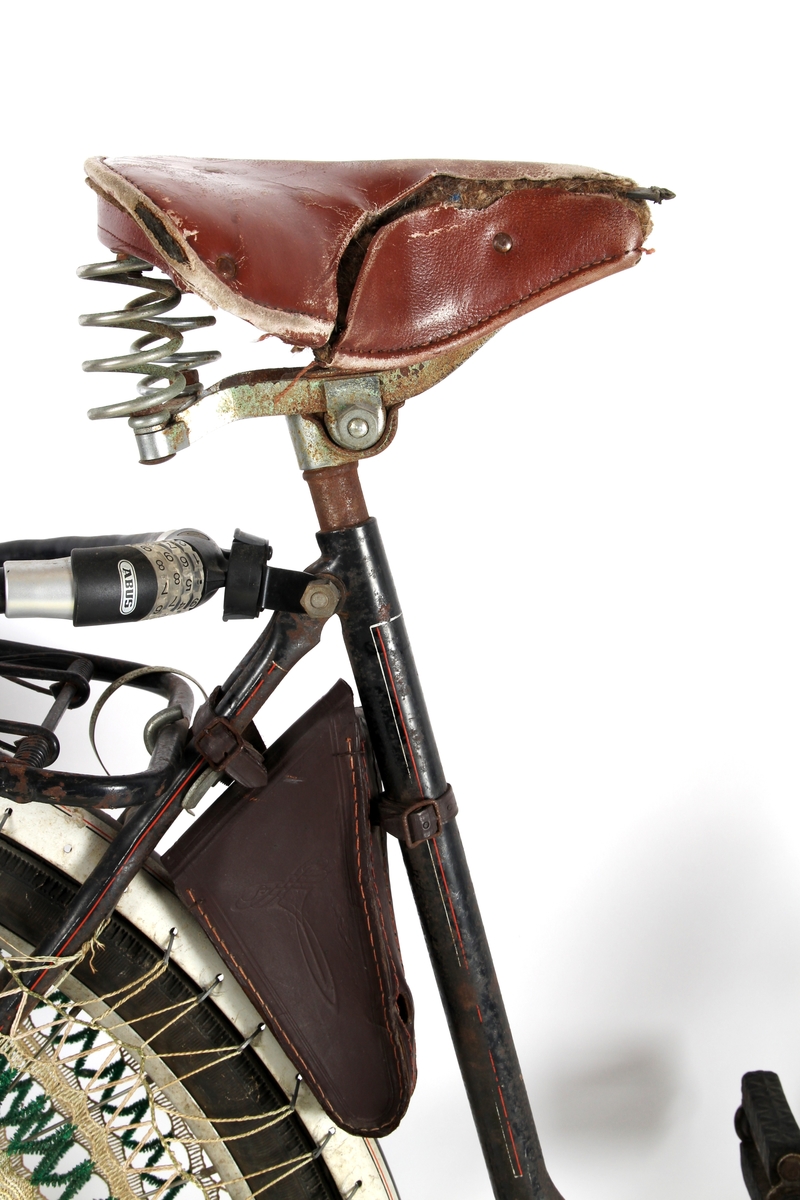 Svartlakkert damesykkel med taske til verktøy under setet og kjolenett på bakhjul. Torpedo frinav med innebygd trommelbrems.