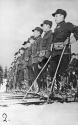 Menn, uniform, ski og skistaver. SKiløpertropp på linje