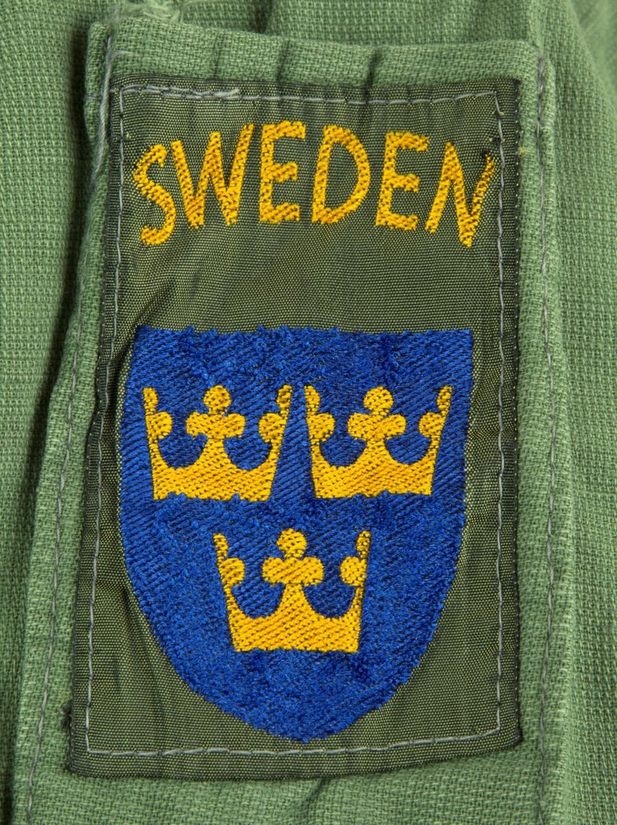 Skjorta i ljus militärgrön, brukad vid FN-tjänst. Två bröstfickor fram med knäppning. Knäppning fram med fyra knappar. Slejf på vardera axel för axelklaffhylsor. På vänster axel (framifrån) sitter ett ljusblått tygmärke med FN logga, på höger axel sitter ett tygmärke med Svensk vapensköld och texten "SWEDEN" i gult. Storlek XL.