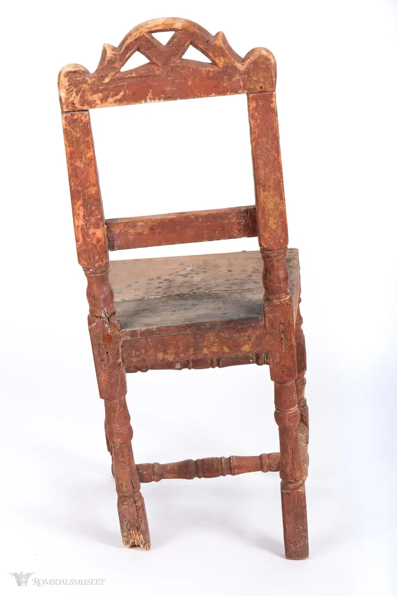 Krone med symmetrisk utskåret motiv. Volutter på sidene og et organisk motiv i midten.