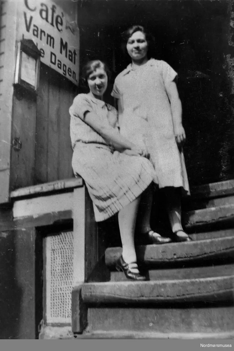 Café, varm mat hele dagen. To jenter i trappa, kanskje gjester, kanskje ansatte. Kristiansund ca 1920.  Nordmøre museums fotosamling