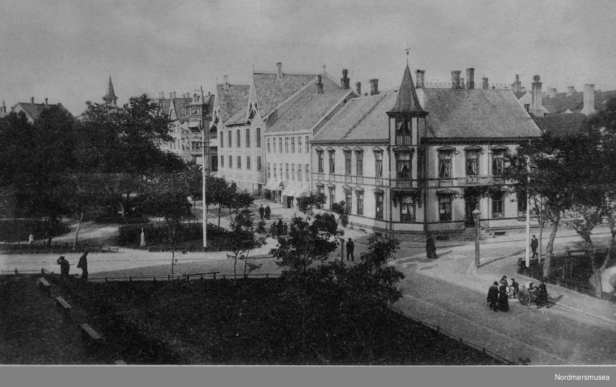 Krysset Langveien/Skolegata: Fastinghjørnet sett fra kirka på Lyhshaugen. Håndkjerre. Folk går i gata. Kristiansund ca 1910-20. Nordmøre museums fotosamling.