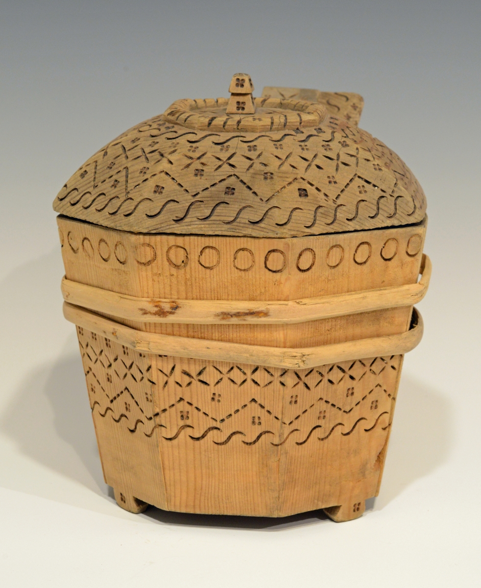 Fra katalog: Ottekantet smørkande og stav med hank og laak og tre smaa føtter, utvendig svimerket og en slynget ring oppe paa laaket, indvendig
rik rosette. Under staar brændemerket: A OSS 1823,