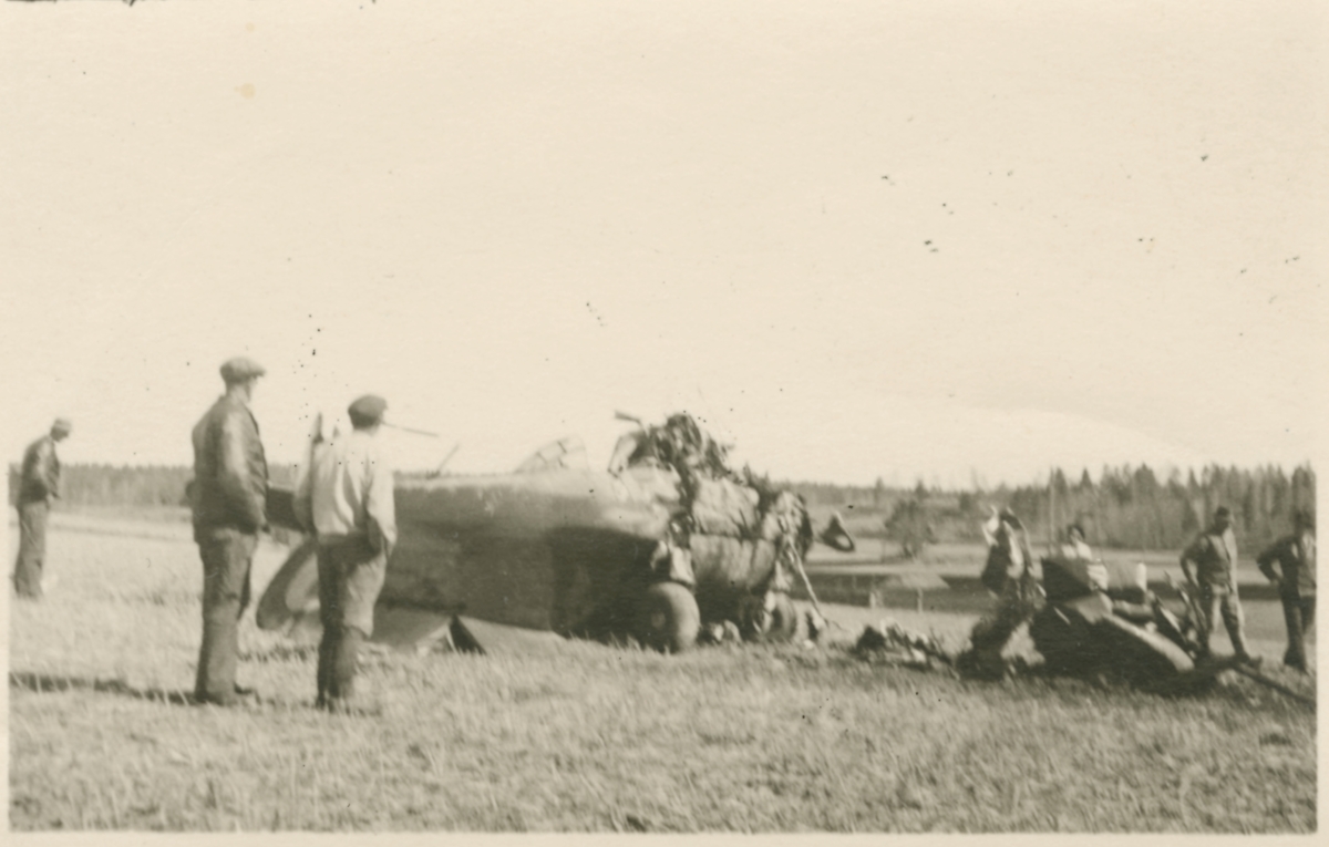 Havererat militärt skolflygplan SK 14 nummer 675, märkt F 5-175 på ett fält utanför Vittsäter, sydost om Nykil i Östergötland, den 30 april 1940. Män i närheten av flygplanet. Serie om 8 bilder.