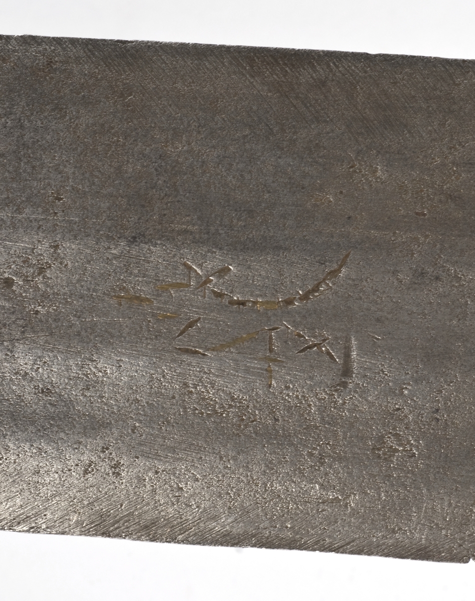 Fasettert rundt knapp med 8 fasetter. Det er innslått 4 smedmerker på knappen, i annethvert felt. Tregrep  Asymerisk åpen parerring med  bøyler med rektangulært tverrsnitt og med kringlefasong med en ytre og en indre parerring. Ytre ring har utsmidde rektangulære partier med kryssfliling. Ytre og indre ring er låst ved at de er tvunnet sammen i senter. Utsiden er smidd som en plateformet deksel. Denne typen pareranordning er trolig norsk
Bred tveegget klinge med 3 brodrender på hver side. Klingen er merket med  Solingens løpende ulv, et hjul og 2 andre symboler på begge sider. Klingen er brukket.