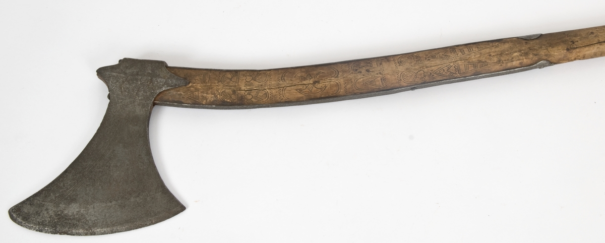 Asymmetrisk blad med lang øvre spiss og kortere nedre spiss.
Bladet er tynt, med påsmidd noe tykkere egg.
Øksehammeren har skaftehull og fliker.
Smedmerke formet som et skjell. Øksen har etset rankedekor på begge sider.
Skaftet er svakt krummet med skinner på rygg-og forside Skinnene har dekor i form av små halvmåner og S. Skaftet er merket ANNO 1758 THS. Skaftet har skåret dekor i felter. Skaftet har doppsko og pigg.