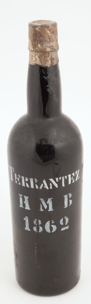 Madeiraflaske med innhold. Stensilerad trykket etikett med hvite bokstaver.
