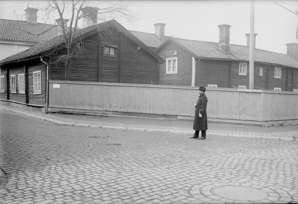 Konstapel i korsningen av Ågatan och Platensgatan i Linköping. I bakgrunden ses Ågatan 53 och delar av bebyggelsen på Platensgatan 4. Dokumenterad av Östergötlands museum inför sanering 1927.