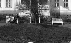 Uidentifisert kvinne og mann foran et våningshus. Fire bilde