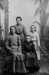 Gruppeportrett av voksen kvinne med tre jenter. To sittende 